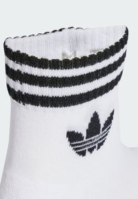 Hvite bomullssokker med sorte striper øverst og en svart logo. Har en teksturert, ribbestrikket mansjett og en glatt kroppdesign.