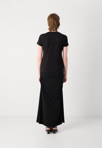 Black short-sleeve top paired with a long black skirt featuring draped detailing, smooth texture, and a straight silhouette.