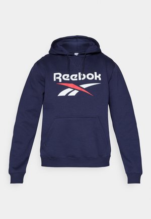 Marineblå hættetrøje lavet af blødt stof, med en frontlomme, snoretræk til hætten og et stort Reebok-logo i hvidt og rødt.