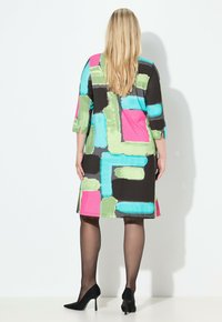 Monivärinen mekko, jossa geometrinen kuvio vaaleanpunaisena, vihreänä ja sinisenä mustalla pohjalla; puolipitkät hihat, polven mittainen leikkaus.