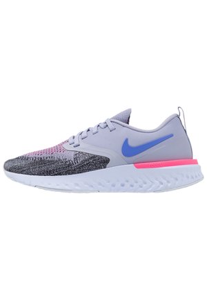 Chaussure de course Nike grise et noire avec un logo bleu, un accent rose près du talon, une semelle blanche texturée et une tige en tissu tricoté.