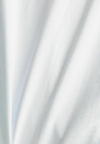 Tissu en coton blanc avec une texture lisse, présentant de légères rides et plis, créant de la profondeur et de la dimension dans le matériau.