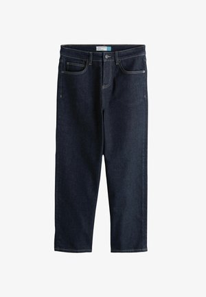 Tumed sinised sirge säärega pahkluude teksad esitaskute, vööaasa ja nööp-lukuga valgel taustal.