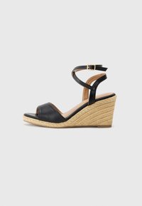 Black leather wedge sandal with an open toe, jute-wrapped heel, and crisscross ankle straps. Smooth texture with a light brown insole.