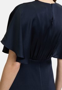 Navyblaues Kleid mit kurzen, schwingenden Ärmeln und einem strukturierten Stoff. Verfügt über einen Knopfverschluss auf der Rückseite und eine taillierte Silhouette.