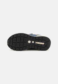 Fekete gumi sneaker talp, textúrált csúszásgátló mintával. Cirkuláris fehér logóval és általánosan masszív dizájnnal a tapadás érdekében.