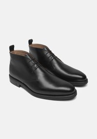 Stivali alla caviglia in pelle nera con finitura liscia, caratterizzati da una punta arrotondata, chiusura con lacci frontale e linguetta sul tallone. Design classico.