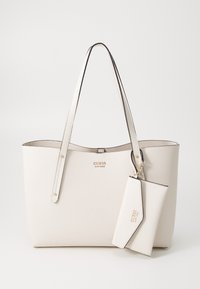 Sac fourre-tout en faux cuir blanc à pois avec des accents dorés, deux poignées et une petite pochette assortie attachée. Présente un logo de marque embossé.