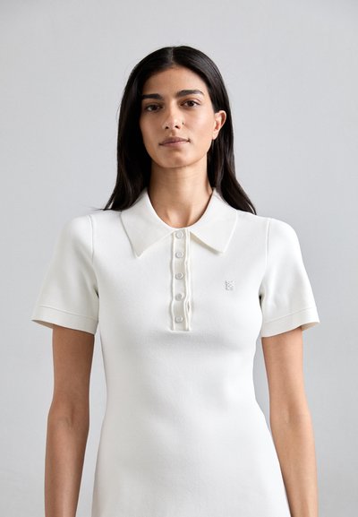 Witte polo met korte mouwen, gemaakt van gebreid materiaal, met een kraag, knoopsluiting en een klein logo op de borst.