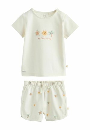 Cream toddler outfit with short-sleeve shirt featuring sun, turtle, palm tree, and "my first holiday" text, paired with matching printed shorts.