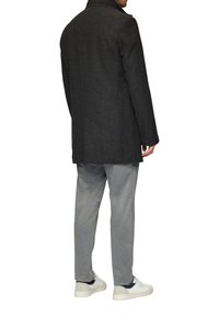 Donkergrijze wolmix jas met een subtiel visgraatpatroon, voorzien van een hoge kraag, gecombineerd met lichtgrijze joggingsbroeken en witte sneakers.