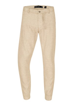 Pantalones estilo jogger color beige, hechos de tela texturada, con puños elásticos, cierre de botón y bolsillos laterales discretos.