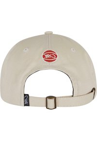 Casquette beige avec une visière courbée, sangle réglable, logo circulaire rouge à l'arrière et accents brodés. Le tissu a une finition texturée.