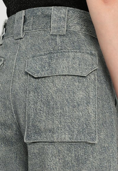 Modri-sivi jeans z visokim pasom, ki imajo velike, pravokotne zadnje žepe in teksturirano tkanino. Čiste šive brez vidnega blagovne znamke.