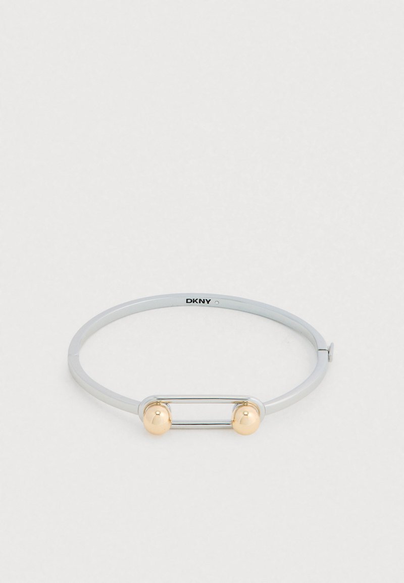 Brazalete de metal plateado con acabado liso, que presenta un detalle rectangular de plata y dos extremos esféricos dorados. Cierre ajustable incluido.