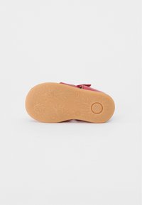 Rød sko med en glat, læderlignende overdel og en gummisål med et struktureret design. Velcro-strop til lukning.