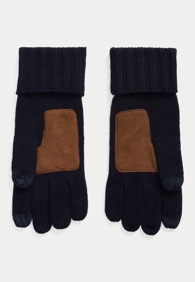 Adītas tumši zilas cimdi ar brūnu ādas plāksteri plaukstai, ribaina aproce un pirkstiem bez dizaina īkšķim un rādītājpirkstam. Teksturēts adīts audums.