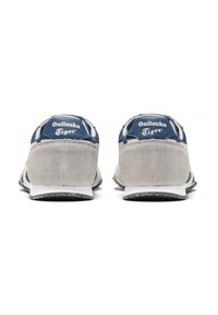 Sneakers Onitsuka Tiger z szarej zamszowej cholewki, niebieskimi akcentami, białym logo na pięcie i teksturowaną gumową podeszwą dla lepszej przyczepności.