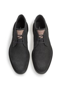 Scarpe nere con lacci in pelle texture. Punta arrotondata, cuciture sottili e un dettaglio in pelle marrone chiaro sulla linguetta con scrittura a mano.