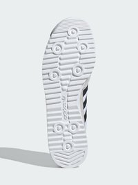 Witte sneakerzool met gestructureerde grip, voorzien van drie zwarte strepen, ronde traction patronen en een glad, afgerond hiel.