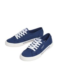 Mornarsko platneno športno obuvalo z belimi vezalkami, okroglo gumijasto kapico in teksturirano podplato. Ima stranske črte in označbo blagovne znamke na ježku.