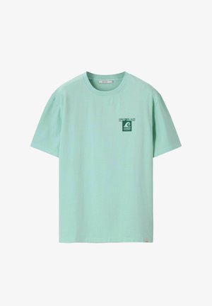 Lichtgroen T-shirt met korte mouwen en een ronde hals, voorzien van een klein donker groen golflogo en de tekst "COPA Y COSTA GALICIA" op de linkerborst.