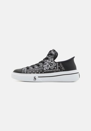 Sneaker basse bianco e nero con motivo paisley, lacci neri, suola bianca spessa e collo del tallone nero rialzato.