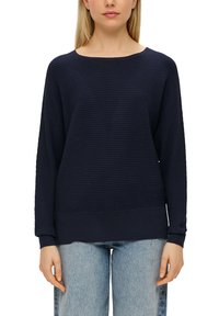 Marineblauer gerippter Pullover mit langen Ärmeln, weitem Halsausschnitt und lockerer Passform, kombiniert mit hellblauen weiten Jeans. Strukturierte Stoffoberfläche.