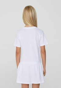 Kurzärmliges, weißes Baumwinkelkleid mit lässigem Schnitt und ausgestelltem Saum, das über einen einfachen Rundhalsausschnitt und eine glatte Textur verfügt.