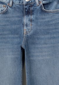 Jeans in denim azzurro chiaro con una texture sbiadita, dotati di cuciture arancioni, design a cinque tasche e chiusura frontale con bottone.