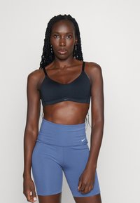 Svart sportsbh med justerbare stropper, kombinert med høytaljede, blå sykkelshorts med en liten hvit logo på livet.