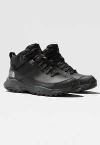 Botas de senderismo de caña alta negras, fabricadas con materiales sintéticos y de malla. Incluyen una suela de goma texturizada, diseño con cordones y acentos de marca.