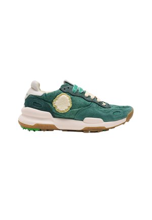 Zapatilla de ante verde con cordones crema, detalles en blanco y verde, suela gruesa blanca y marrón, y un parche circular texturizado en el lateral.