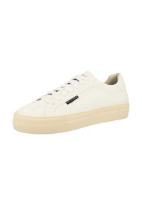 White leather sneakers with a thick beige rubber sole, featuring rounded toe, flat laces, and a black brand tag on the side.