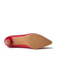 Suela de zapato de cuero rojo con un acabado suave, que presenta una suela de goma marrón claro con un diseño de agarre patternado.