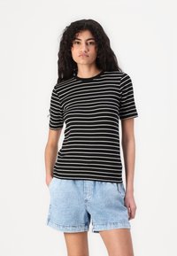 Black and cream striped short-sleeve t-shirt with a round neckline, paired with light blue denim shorts. Soft cotton material.