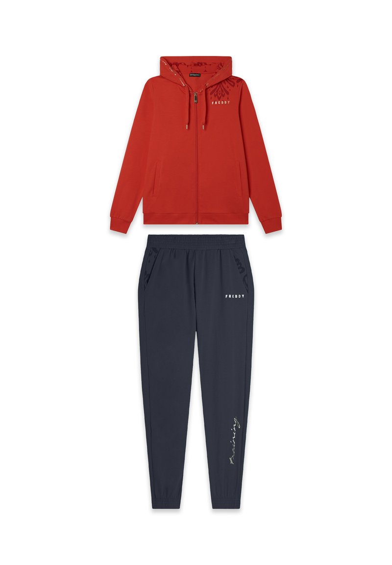 Sudadera roja con cremallera y capucha, con bolsillos laterales, combinada con pantalones jogger marinos con cintura elástica y un detalle de texto estampado.