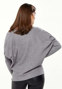 Gray oversized sweater with a lightweight, soft texture and loose sleeves. Ribbed cuffs and hem complement the relaxed fit.