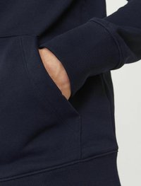 Dunkelblaues Sweatshirt mit strukturiertem Stoff, gerippten Bündchen und einer Fronttasche. Das Design ist lässig und praktisch für den Alltag.