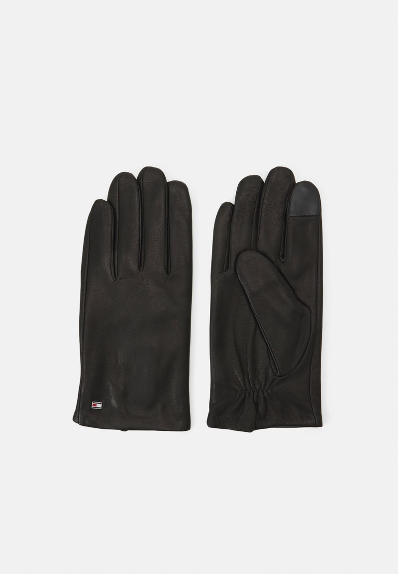 Black leather gloves with five fingers, elasticized wrist, and a textured grip detail on one fingertip. Features small logo tag on wrist.