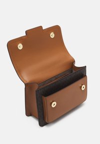 Bruine leren tas met gouden hardware, voorzien van een drukknoopsluiting, een open vak en een patroon met een donkere paneel aan de onderkant.