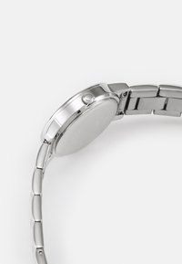 Silver stainless steel watch with a round case, smooth bezel, and a polished bracelet. Features a crown and a simple, clean design.
