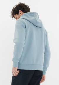 Hellblaues Kapuzensweatshirt mit Kängurutasche, gerippten Bündchen und Saum. Weicher Stoff, minimales Design, schlichte Rückenansicht.