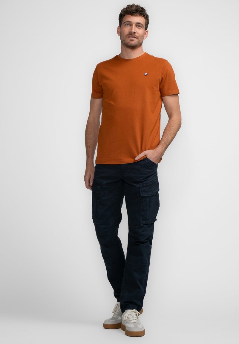 Tangerine kleurige katoenen t-shirt met een ronde halslijn en een klein logo op de borst, gecombineerd met marineblauwe cargo-broeken met meerdere zakken en een ontspannen pasvorm.