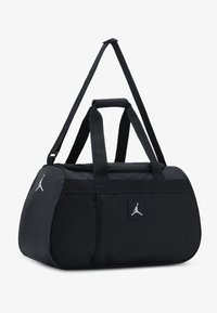 Black duffel bag made from durable material, featuring a rounded shape, dual carry handles, adjustable strap, and a logo patch on the side.