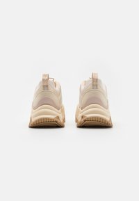 Sneakers chunky con una combinazione di colori beige e rosa chiaro, caratterizzati da una tomaia testurizzata, un'etichetta di estrazione e una spessa suola in gomma per una maggiore aderenza.