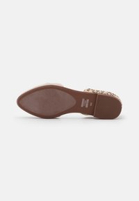 Zapatilla de slip-on con estampado de leopardo, parte superior de tela color marrón, suela de goma texturizada y un leve tacón cuña. Incluye etiqueta de la marca en la suela.