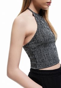 Czarnobiała, paskowana bluzka typu crop top na ramiączkach, z dopasowanym krojem i teksturowanym materiałem, z zapięciem na plecach i wyciętymi bokami.