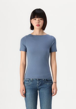 Šviesiai mėlyna trumpa rankovė t-shirt su apvaliu iškirpimu, prigludusiu siluetu ir lygia tekstūra, derinama su tamsiai mėlynomis džinsinėmis kelnėmis.