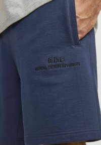 Navy zila šorti kokvilnas maisījumā ar gludu tekstūru. Uz kreisā kabatas ir izcelts "R.D.D. Royal Denim Division".